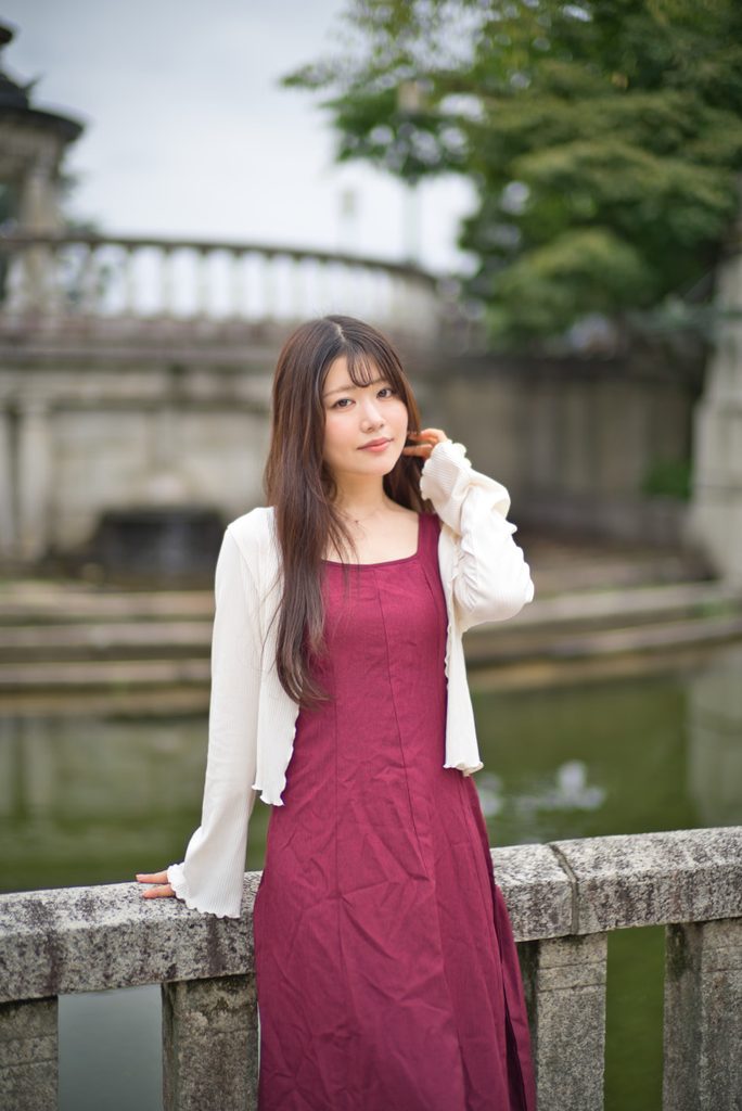 石造りの建築と水面を背景にした桜井こはるさんのポートレート(開放F1.0)