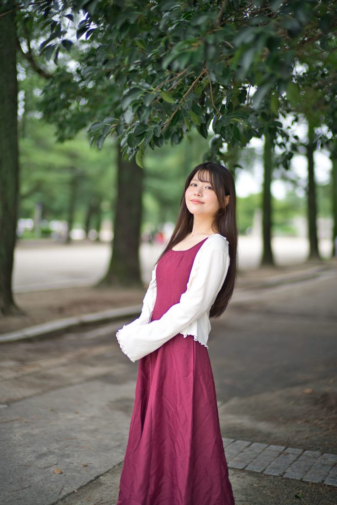 並木道の木漏れ日の中で微笑む桜井こはるさんの全身ポートレート(開放F1.0)