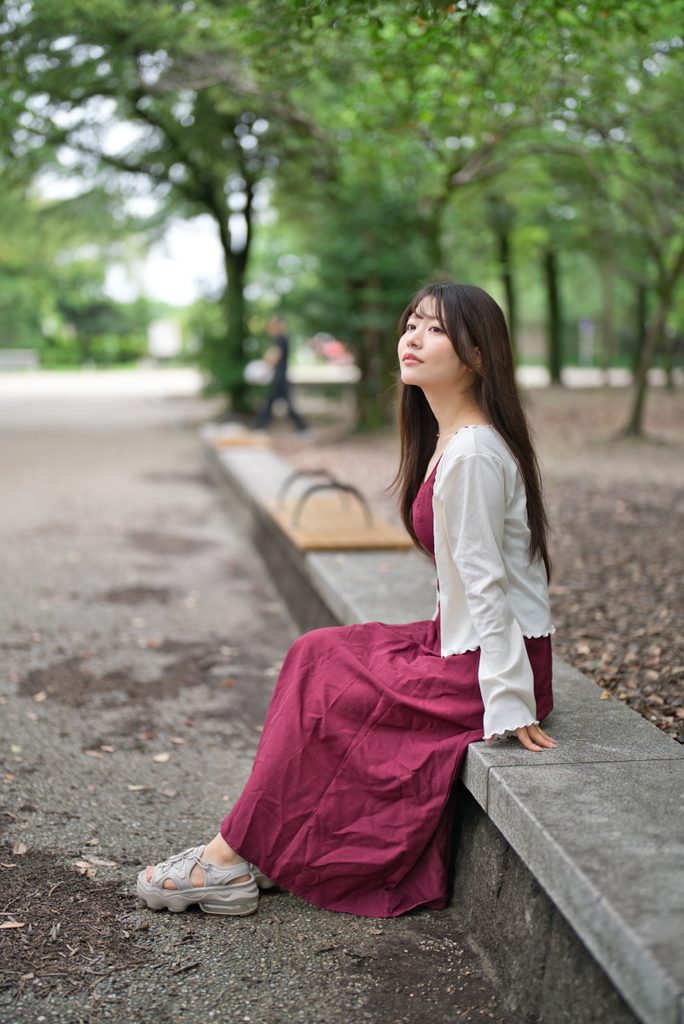 抜けの良い公園の小道を背景にした横顔の開放F1.2ポートレート