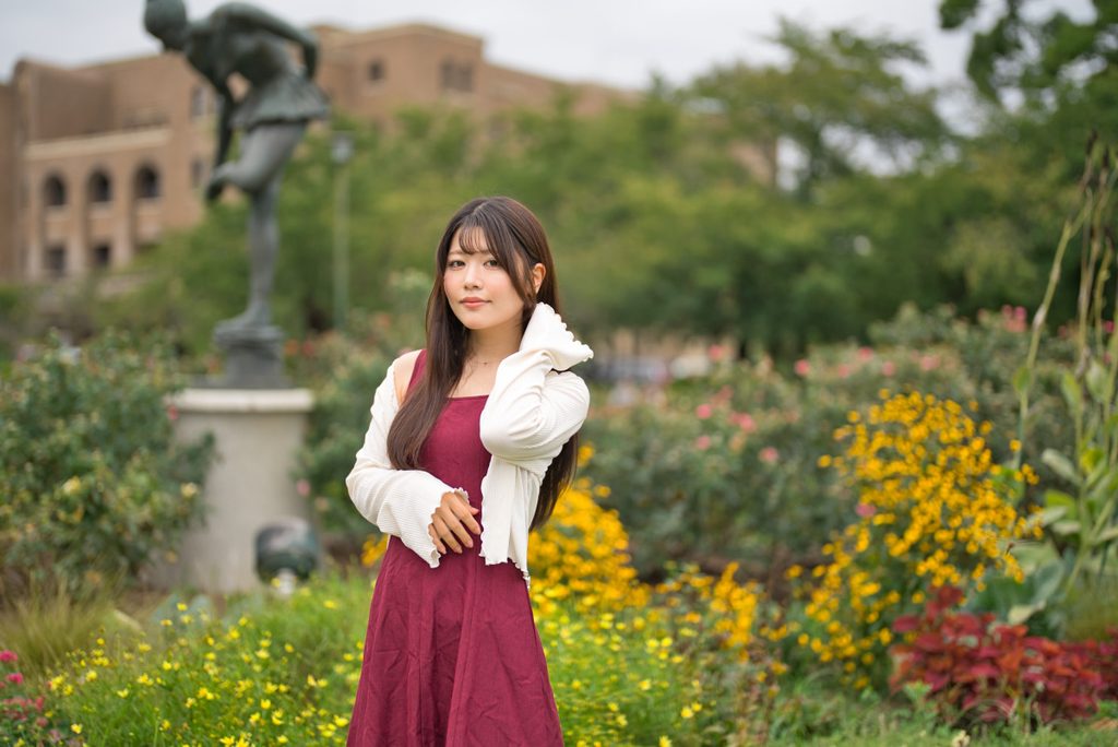 ブロンズ像と花壇を背景に開放F1.2で撮影したポートレート